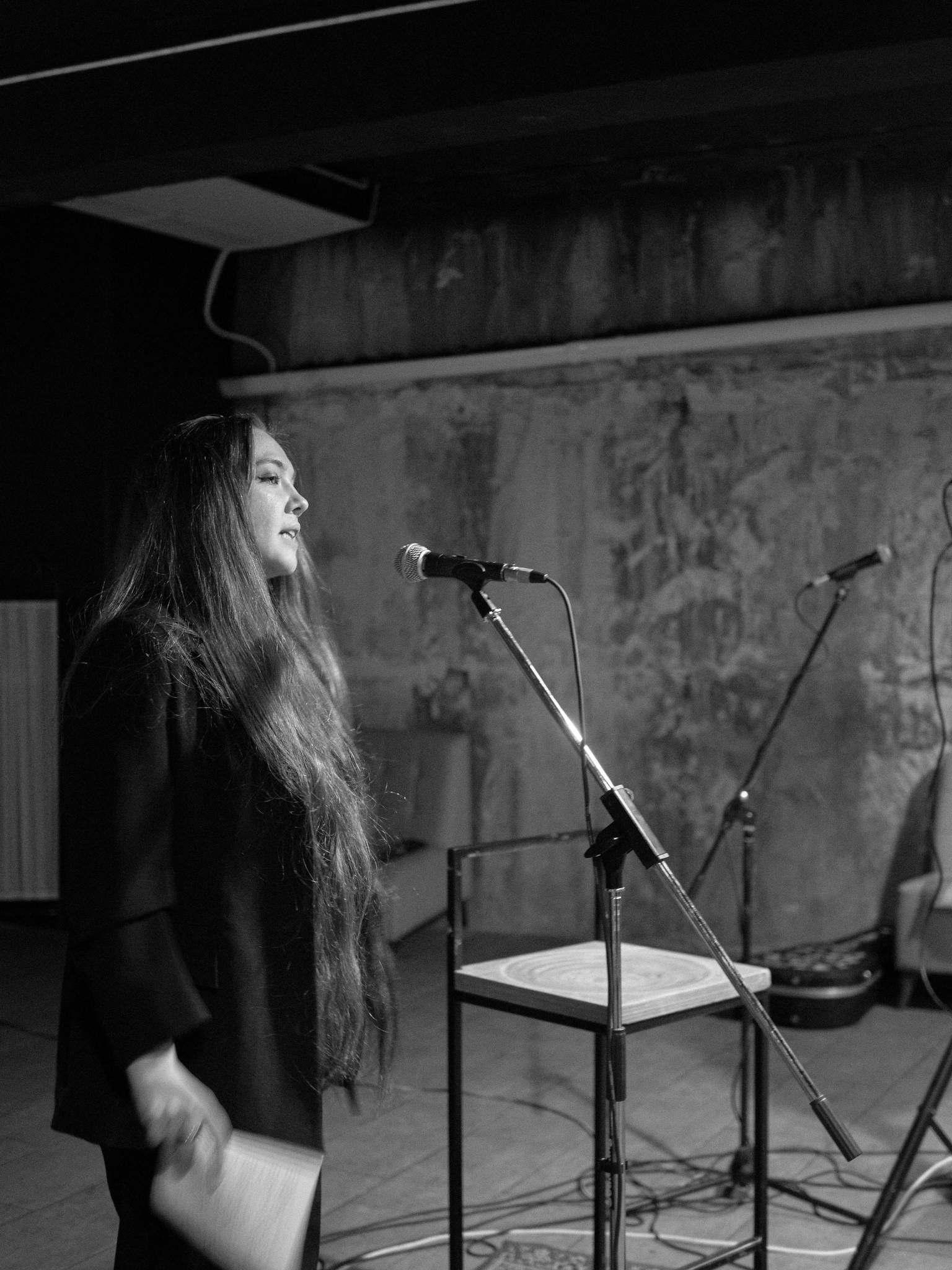 A woman performs with a microphone in a black and white setting.